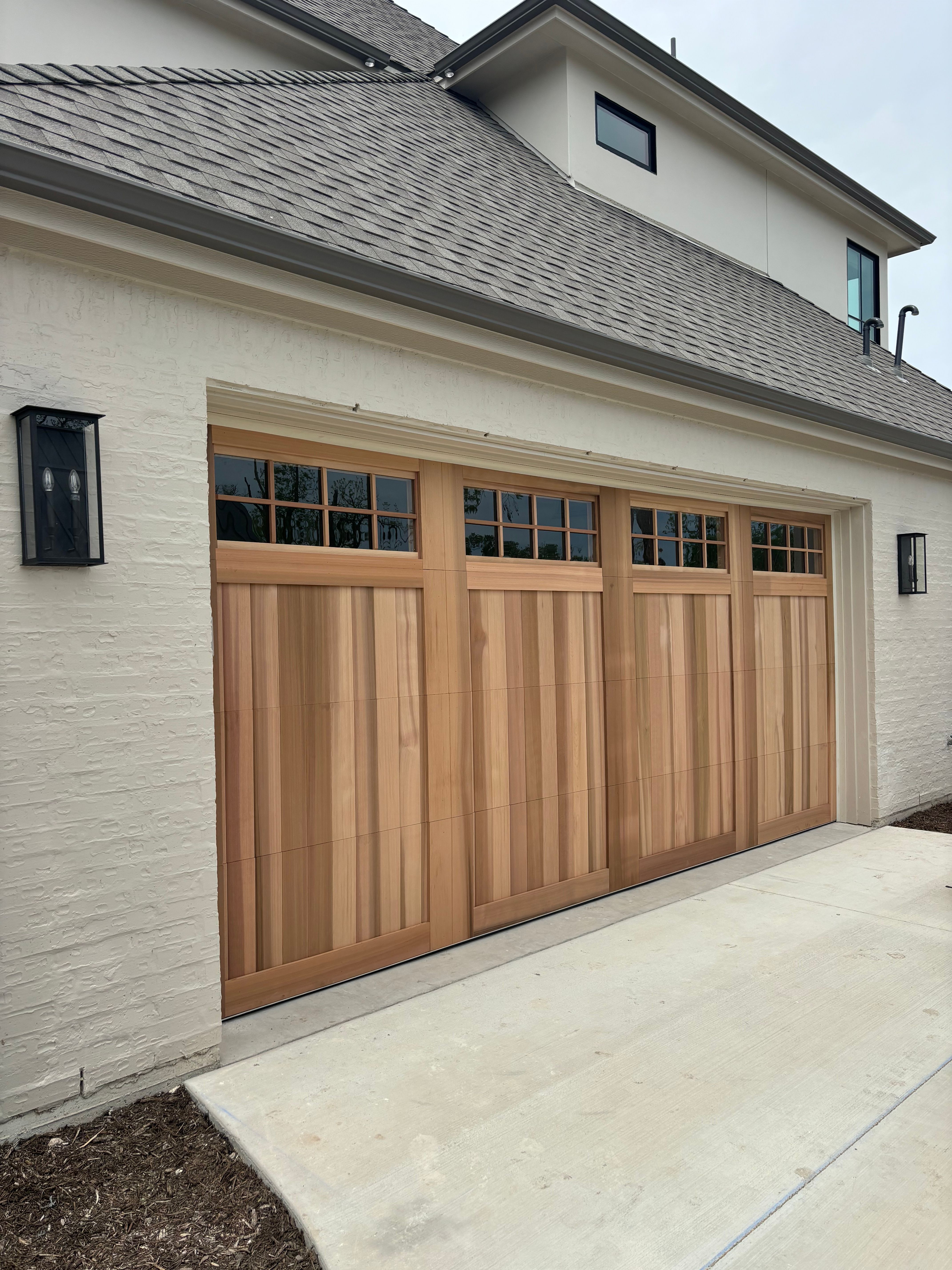 Natural cedar wood garage door with glass windows installed on white stucco home in Central Texas