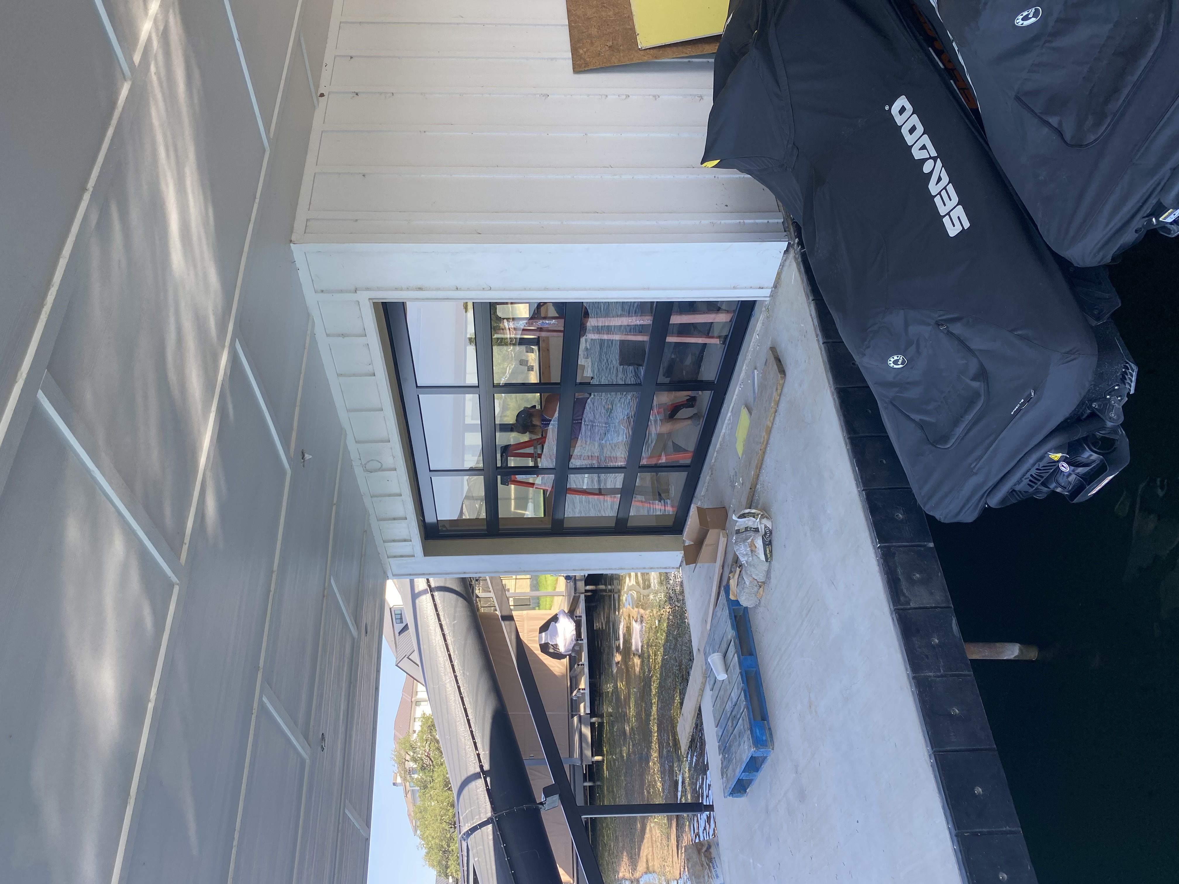 Full-view glass and aluminum garage door installed on lakefront boathouse in Central Texas
