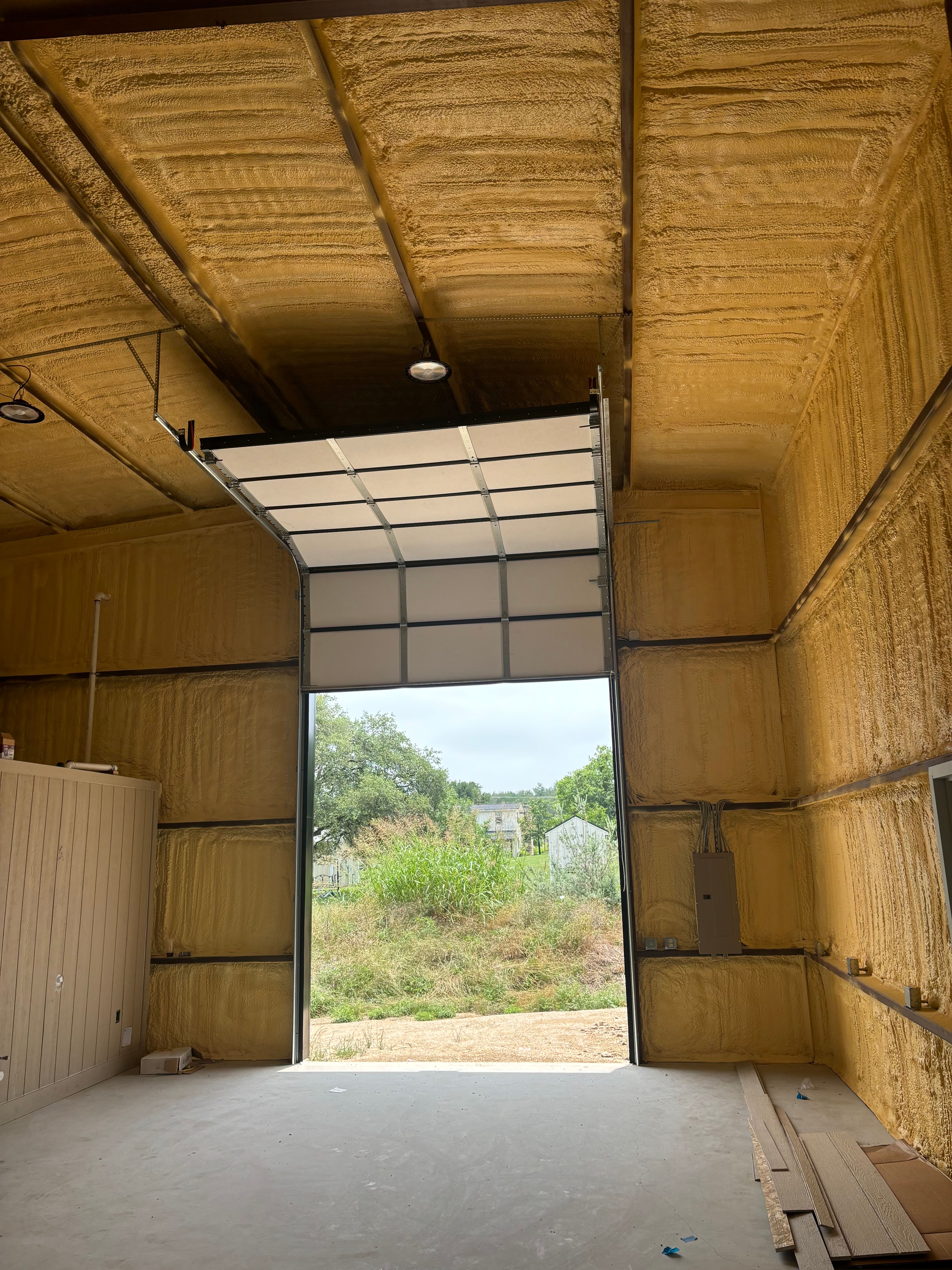 Interior view of large commercial overhead door open in spray-foam insulated industrial building