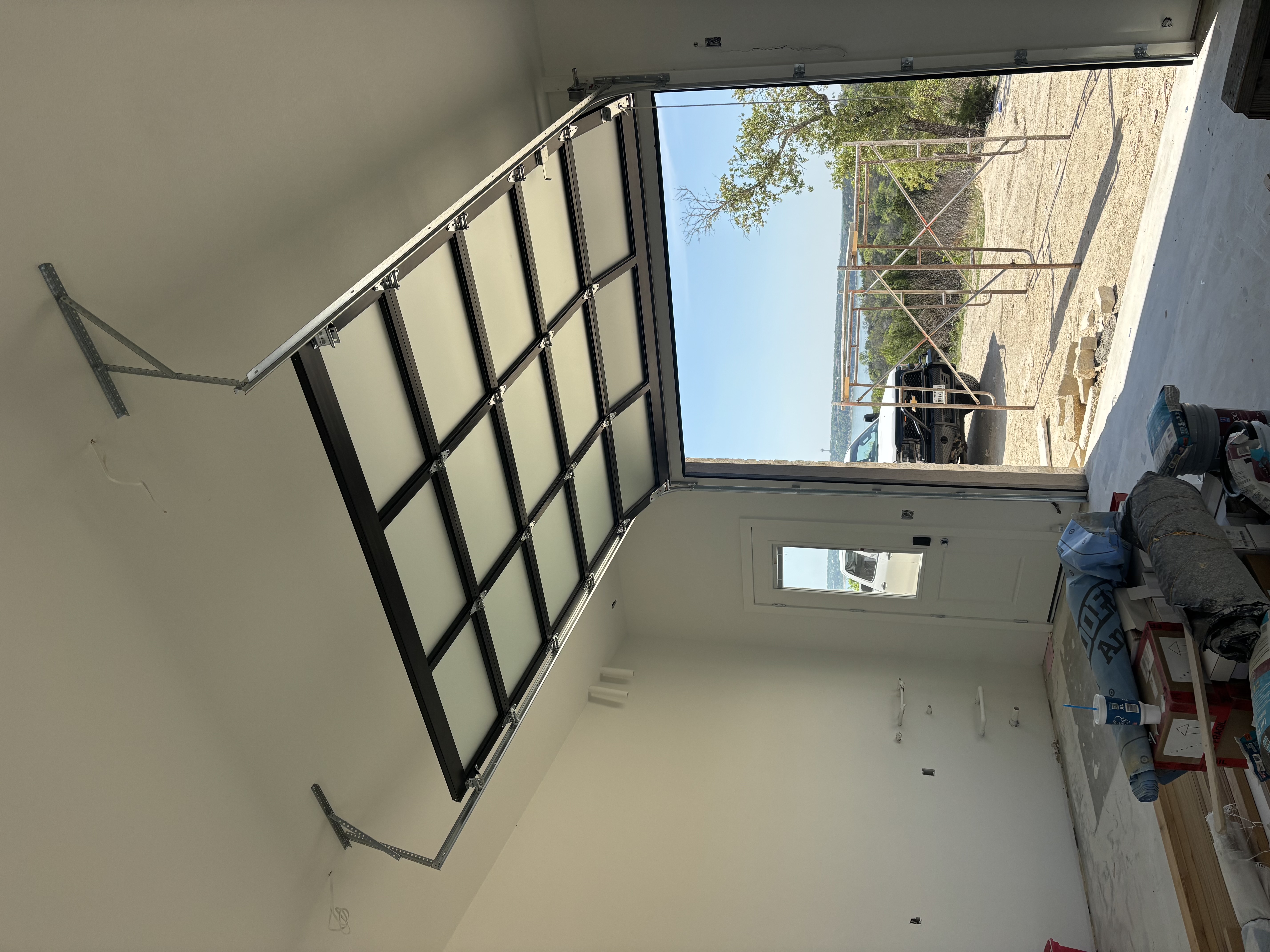 Interior view of full-view glass overhead door open on a lakefront new-construction home in Central Texas, installed by Palousek Overhead Doors