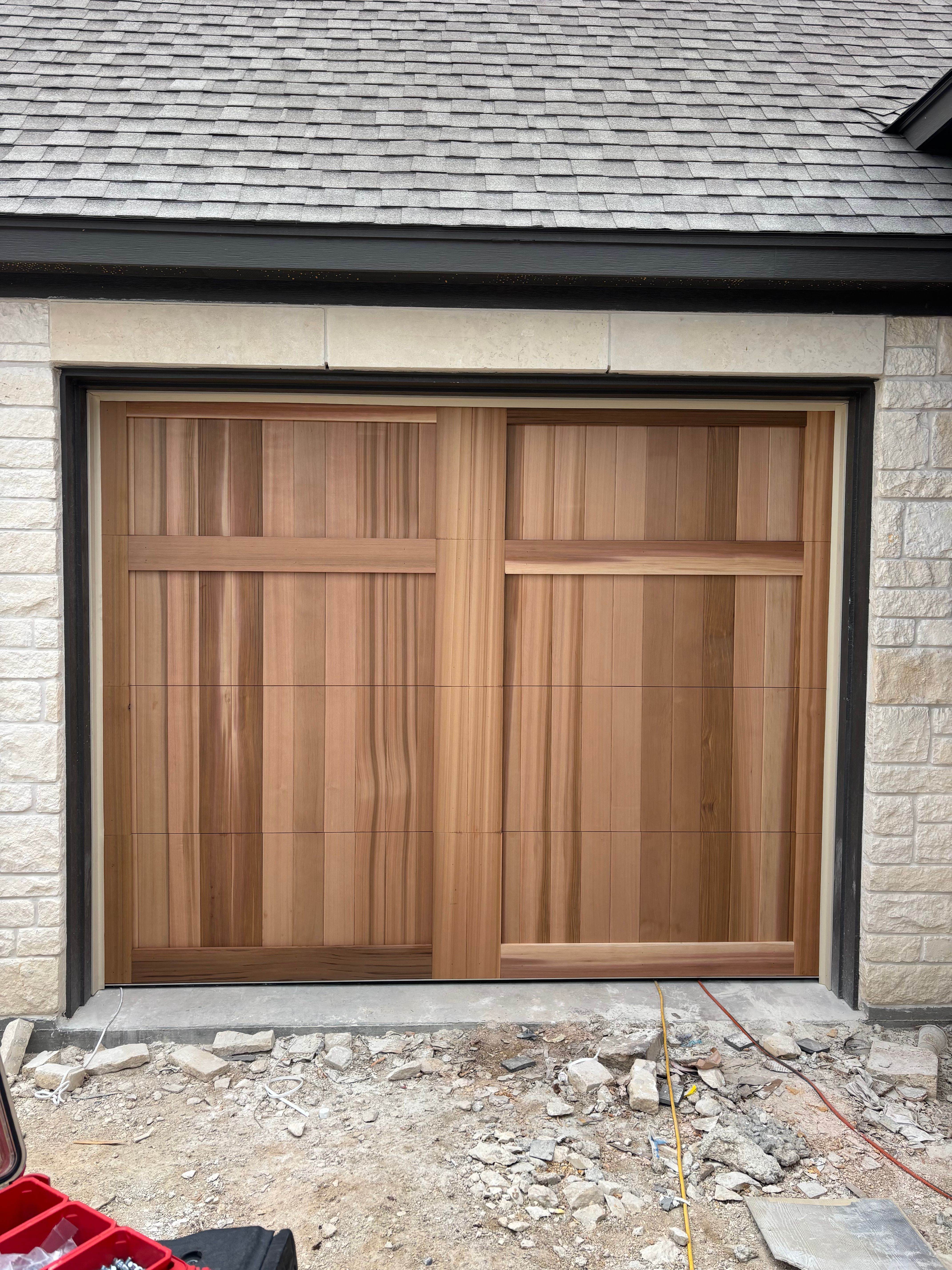 Natural cedar wood garage door without windows installed on a new limestone home in Central Texas by Palousek Overhead Doors